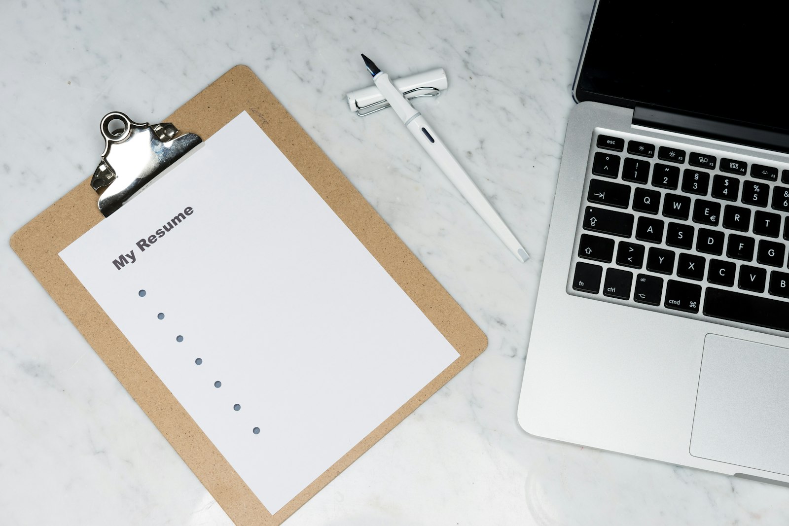 Un CV imprimé posé à côté d'un ordinateur portable sur un bureau clair