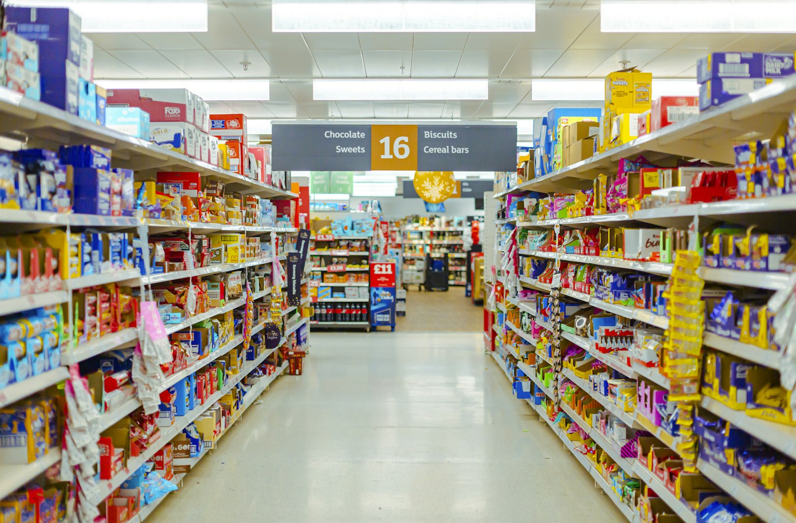 Longue allée de supermarché bordée de rayonnages remplis de produits