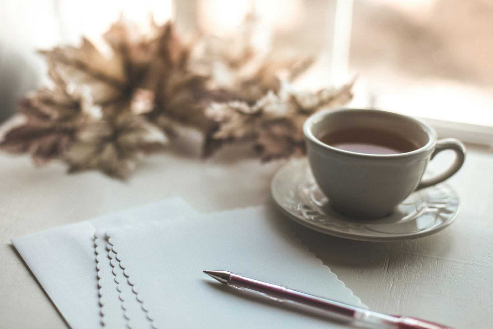 Une tasse posée près d’un carnet et d’un stylo sur un bureau clair