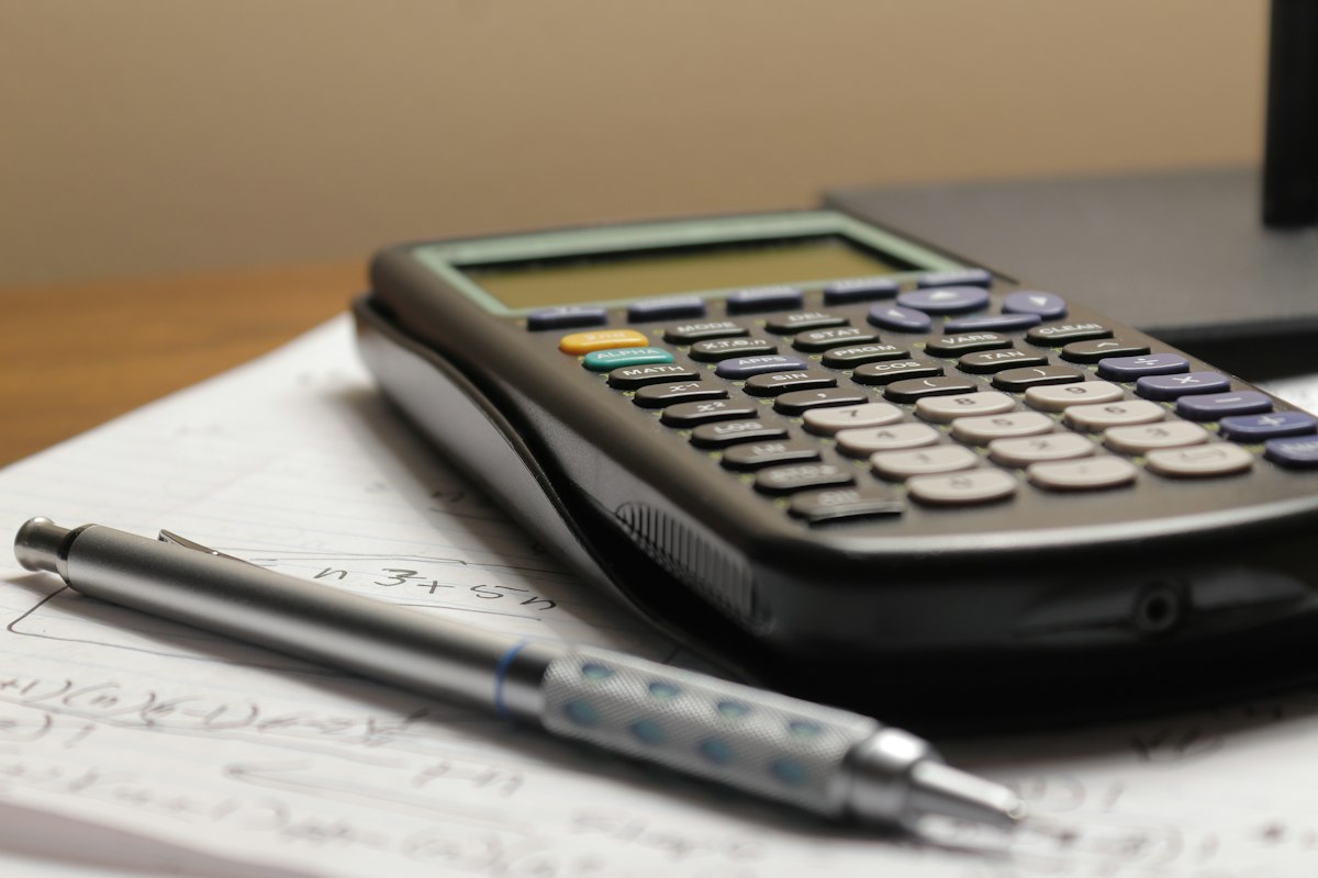 Calculatrice et stylo posés sur des feuilles de calcul