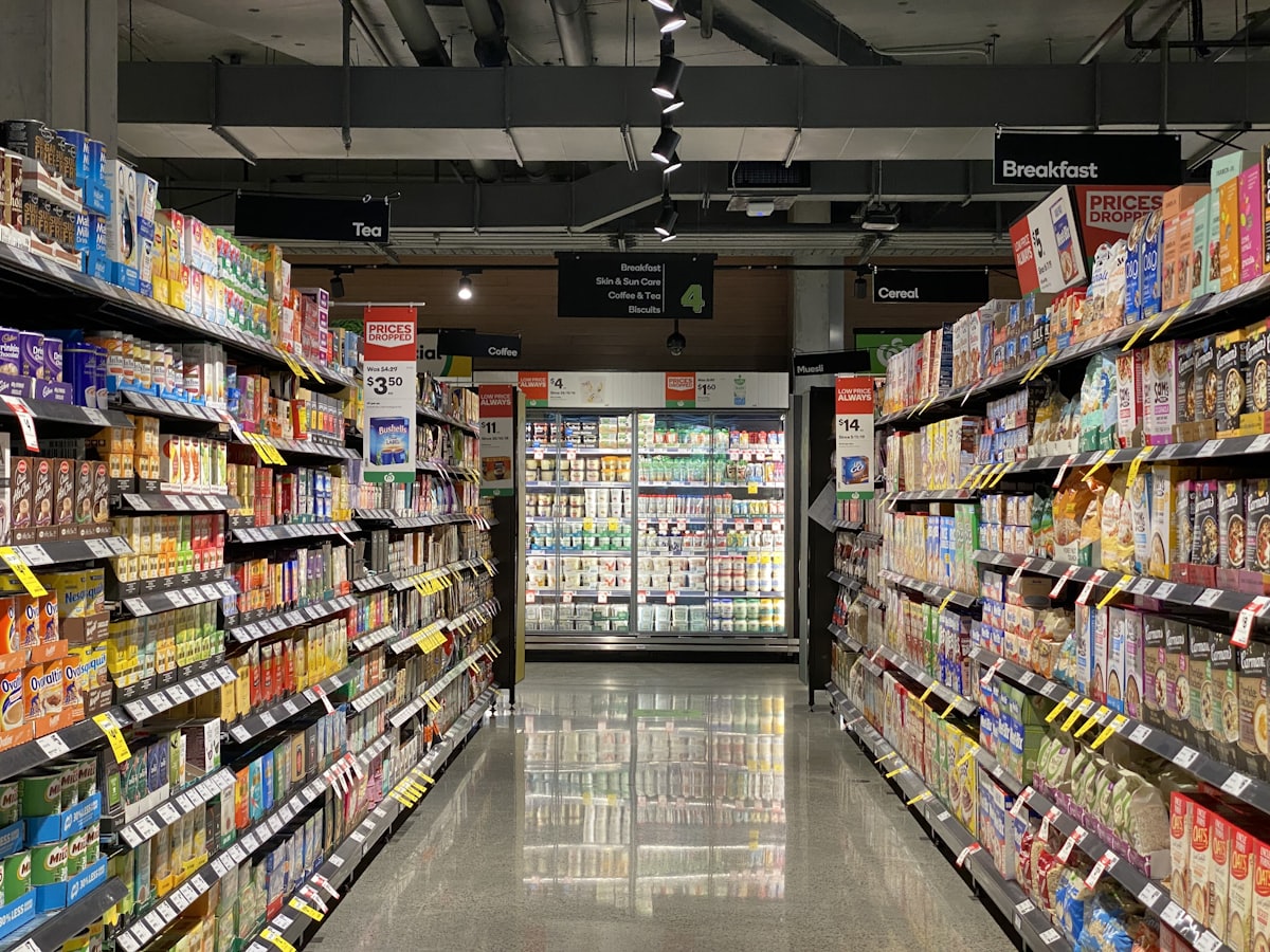 Allée de supermarché bordée de rayons remplis de produits